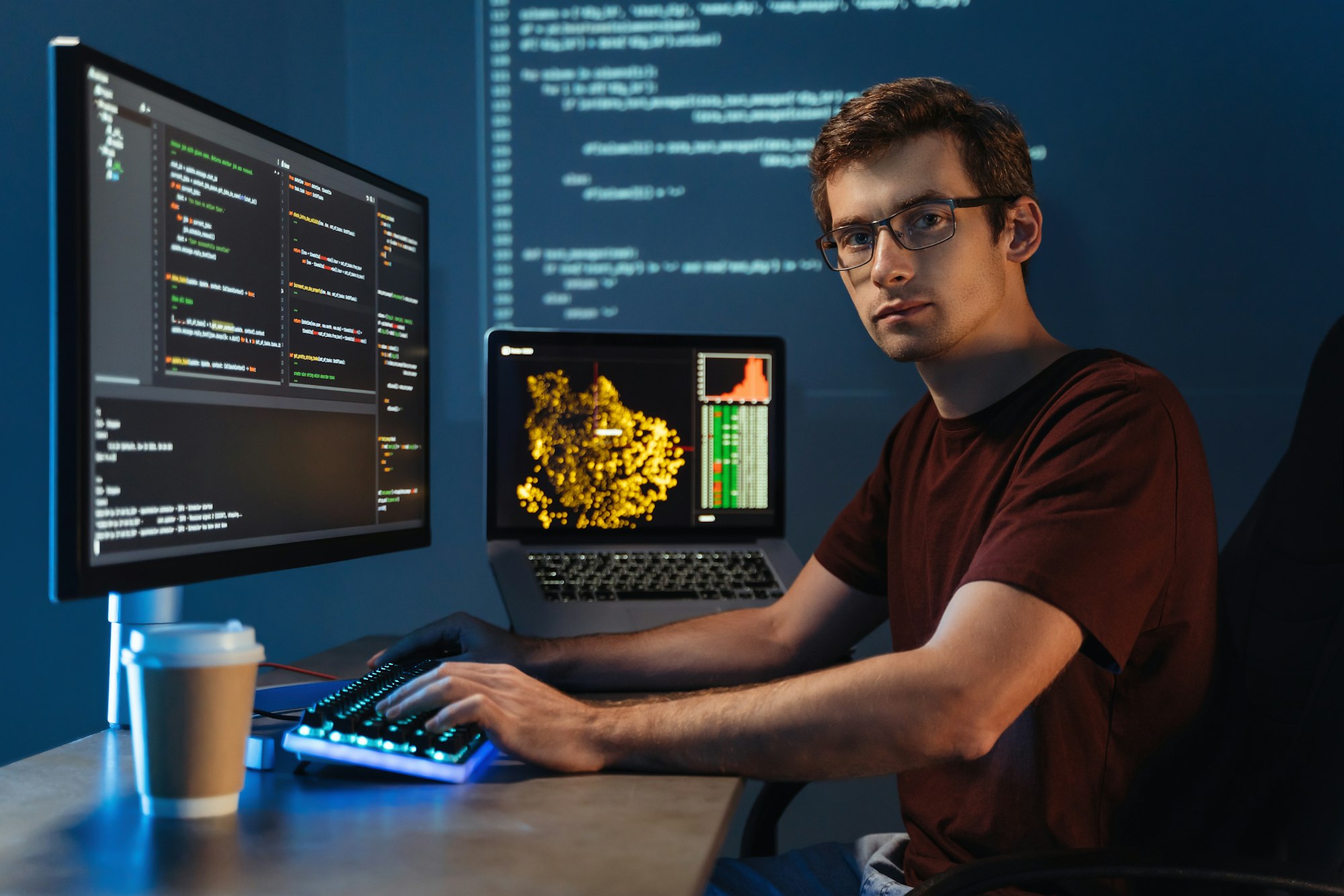 Intelligent male programmer working on pc writing brand new code at home office, looking at camera